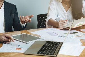 Kaksi ihmistä keskustelee neuvottelutilanteessa tärkeästä liiketoimintaa koskevasta päätöksestä.