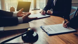 Henkilö istuu vakavana ja pohtii vaikeaa oikeudellista tilannettaan avustajansa kanssa.