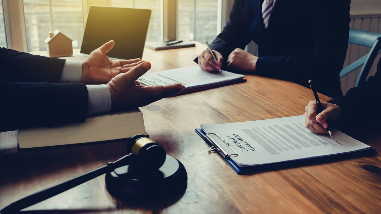 Henkilö istuu vakavana ja pohtii vaikeaa oikeudellista tilannettaan avustajansa kanssa.