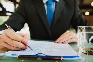 Henkilö allekirjoittaa kauppakirjaa liiketoimintakaupasta