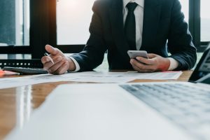 Henkilö istuu työpisteellä mietteliäänä ja arvioi työhön liittyvää päätöstä tai ongelmaa.